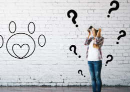 Woman confused as to what a sign means and covering her head with a book. The sign is a pawprint with a heart inside it.